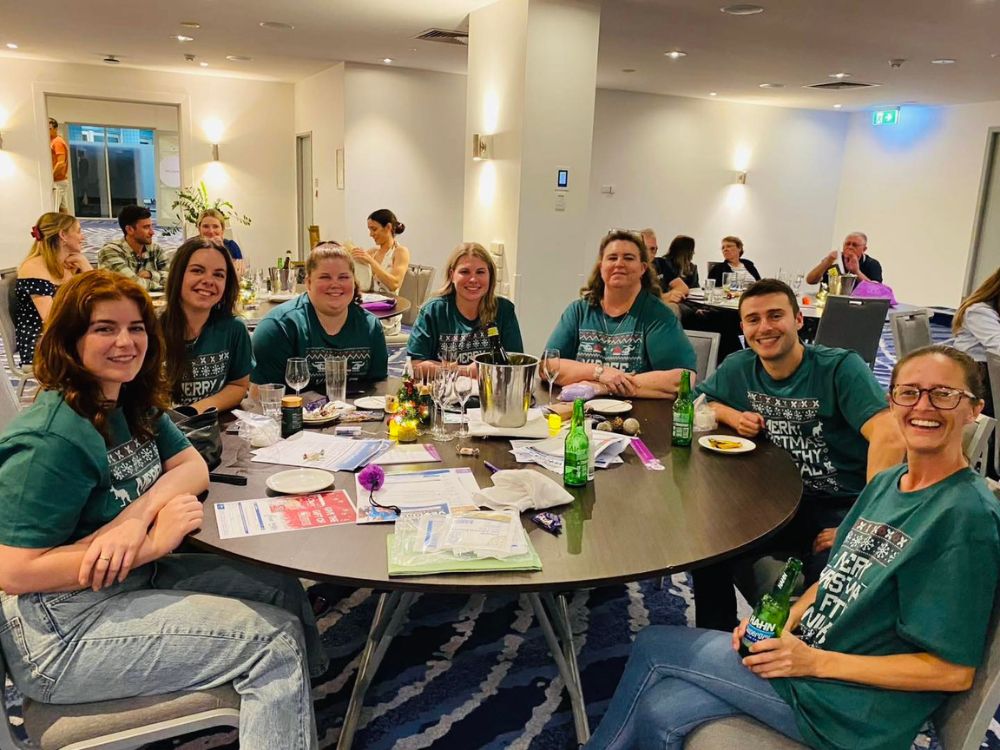 a group of people wearing green shirts sitting at a table