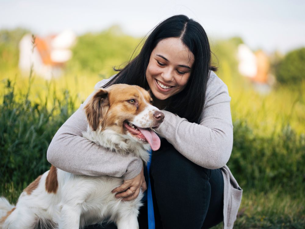 a person sitting on the grass with their dog